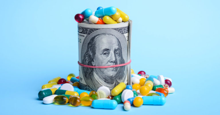 Big pack of dollars surrounded with pills capsules against the blue background. Concept of medicine, medical insurance, health care, infection, drugs